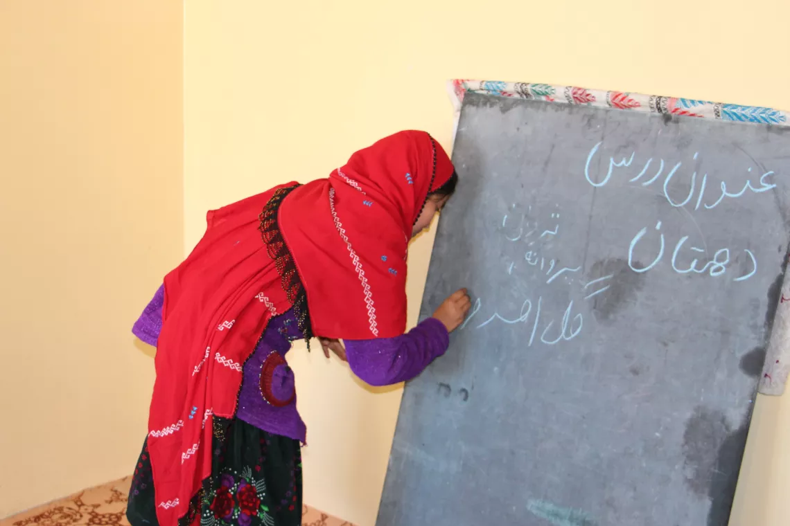 A girl with red scarf practicing her writing skills 