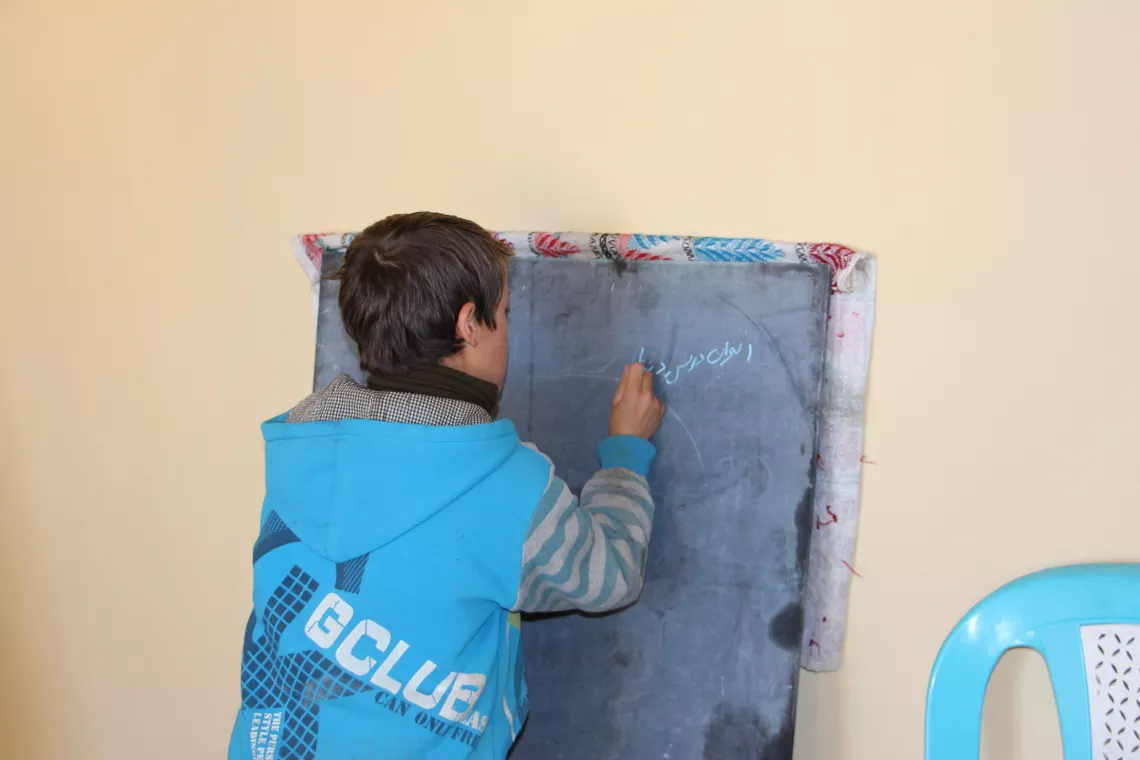 A boy with blue shirt practicing his writing skills 