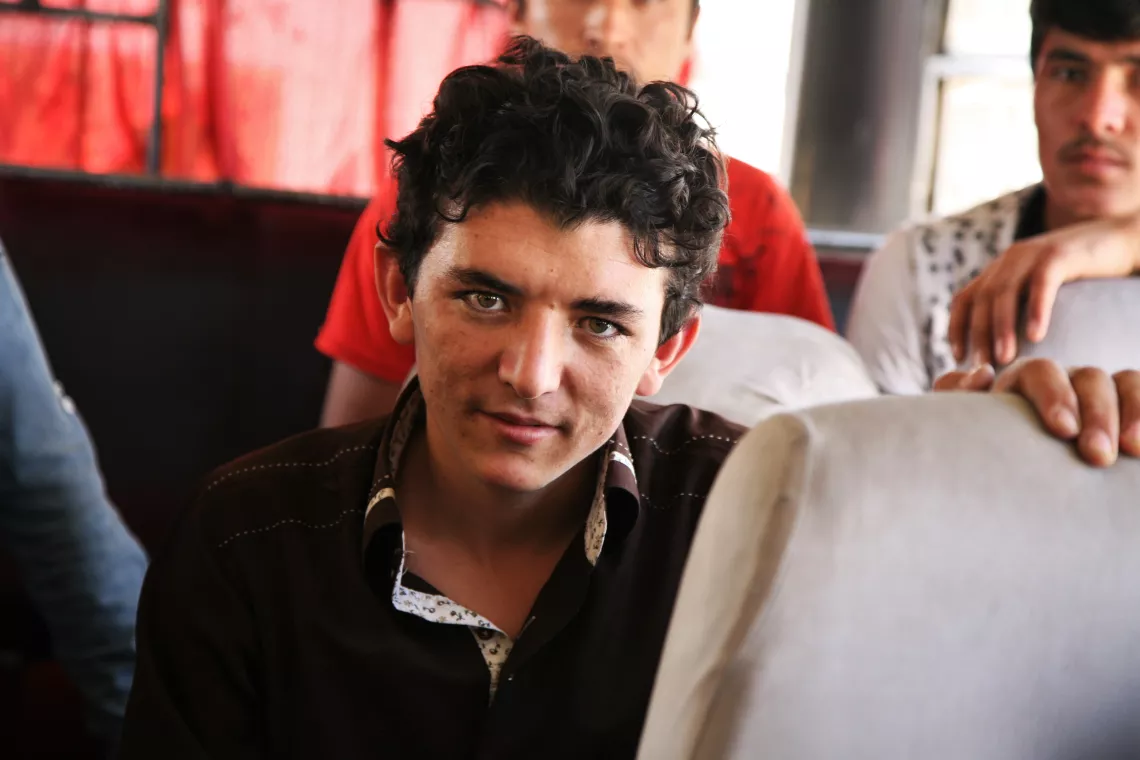 A young male unaccompanied minor poses for photo on a bus at the border between Iran and Afghanistan. 