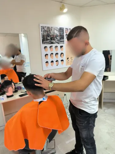 Young hairdresser guy cutting the hair of another boy