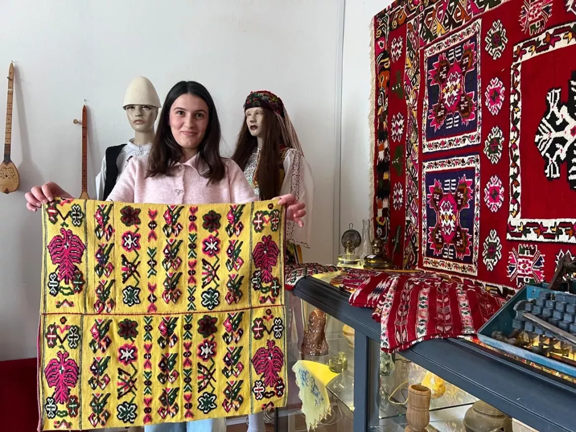 Adolescent girl holding a carpet of the museum
