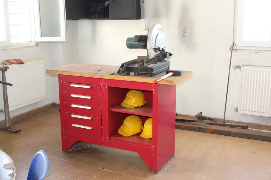 a small red cupboard with working helmets and working tools