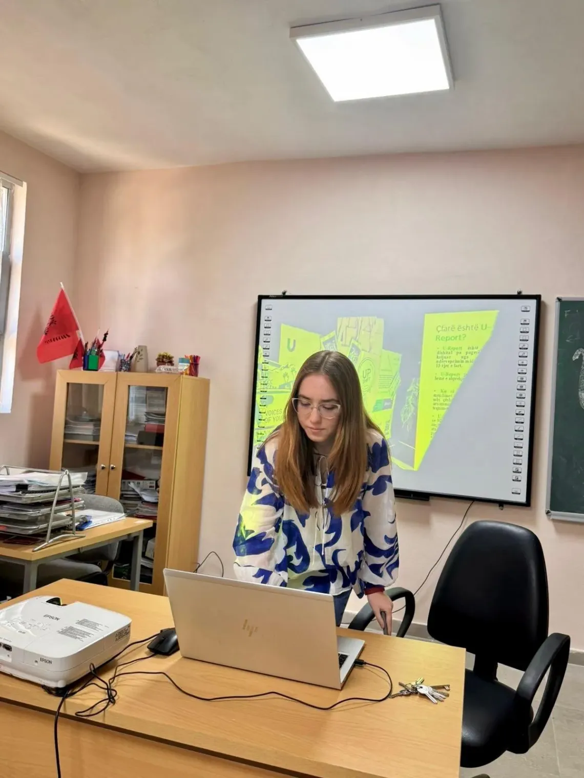 Amelia working on a laptop in her class in front of a screen projector