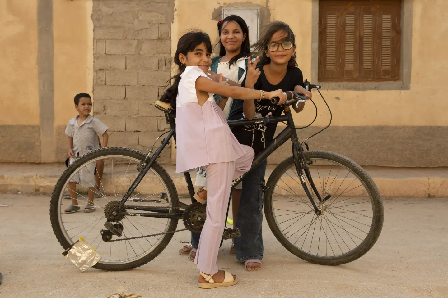 Trois filles devant un v&eacute;lo et un petit gar&ccedil;on qui les regarde
