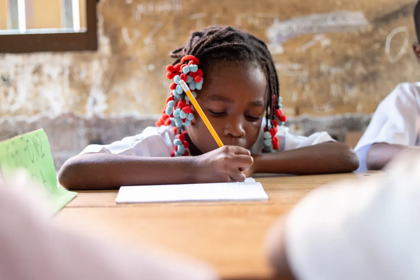 Girls attentively copy lesson from board in a classroom in Luanda