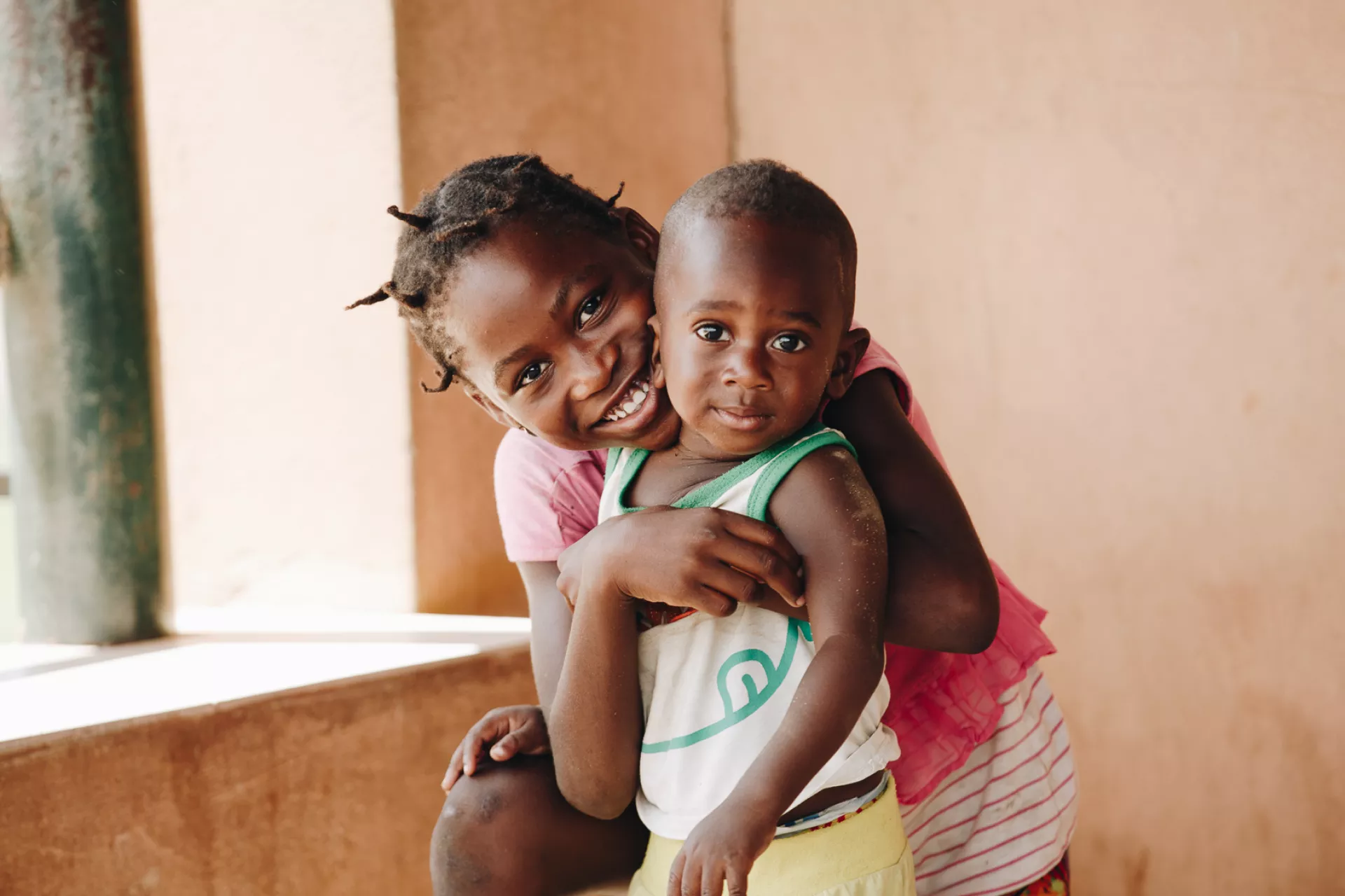 Menina abra&ccedil;a crian&ccedil;a durante a campanha de vacina&ccedil;&atilde;o em Luanda
