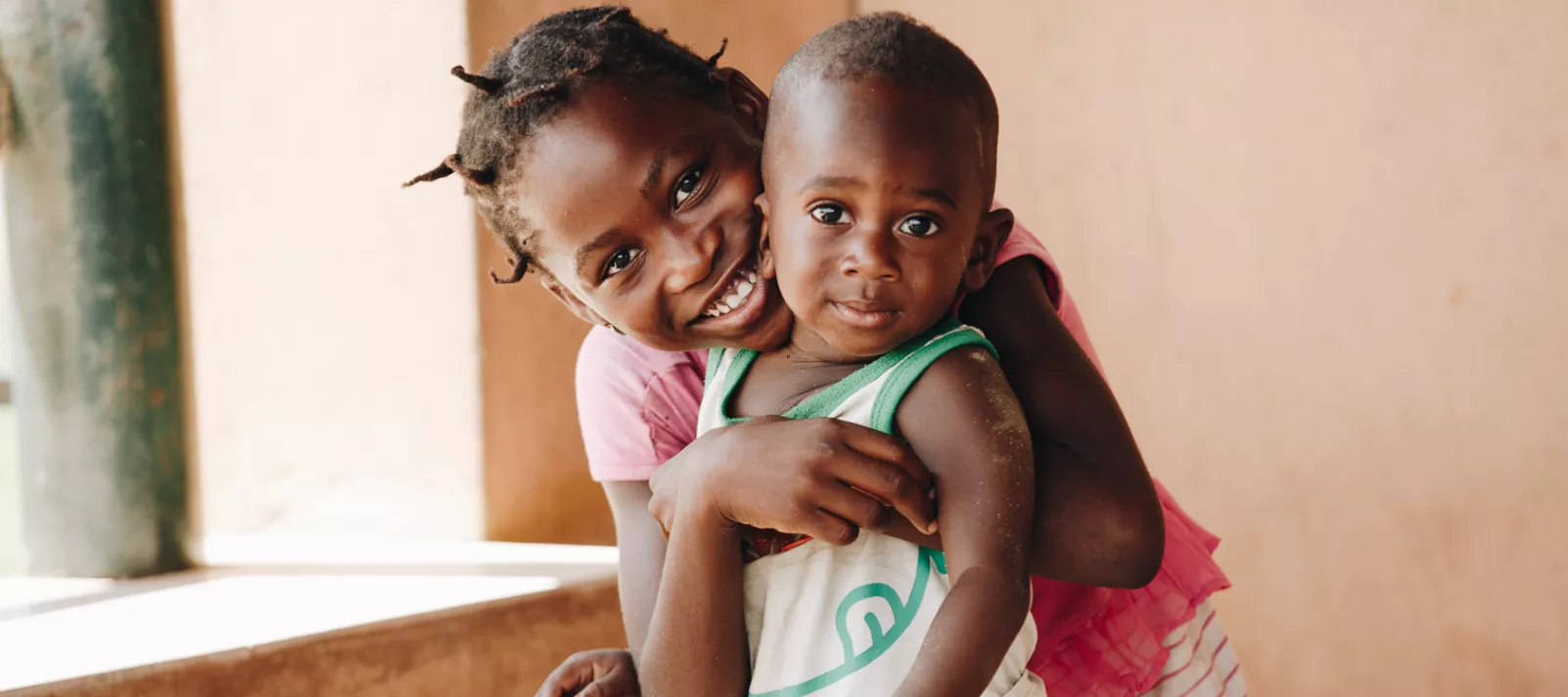 Menina abra&ccedil;a crian&ccedil;a durante a campanha de vacina&ccedil;&atilde;o em Luanda