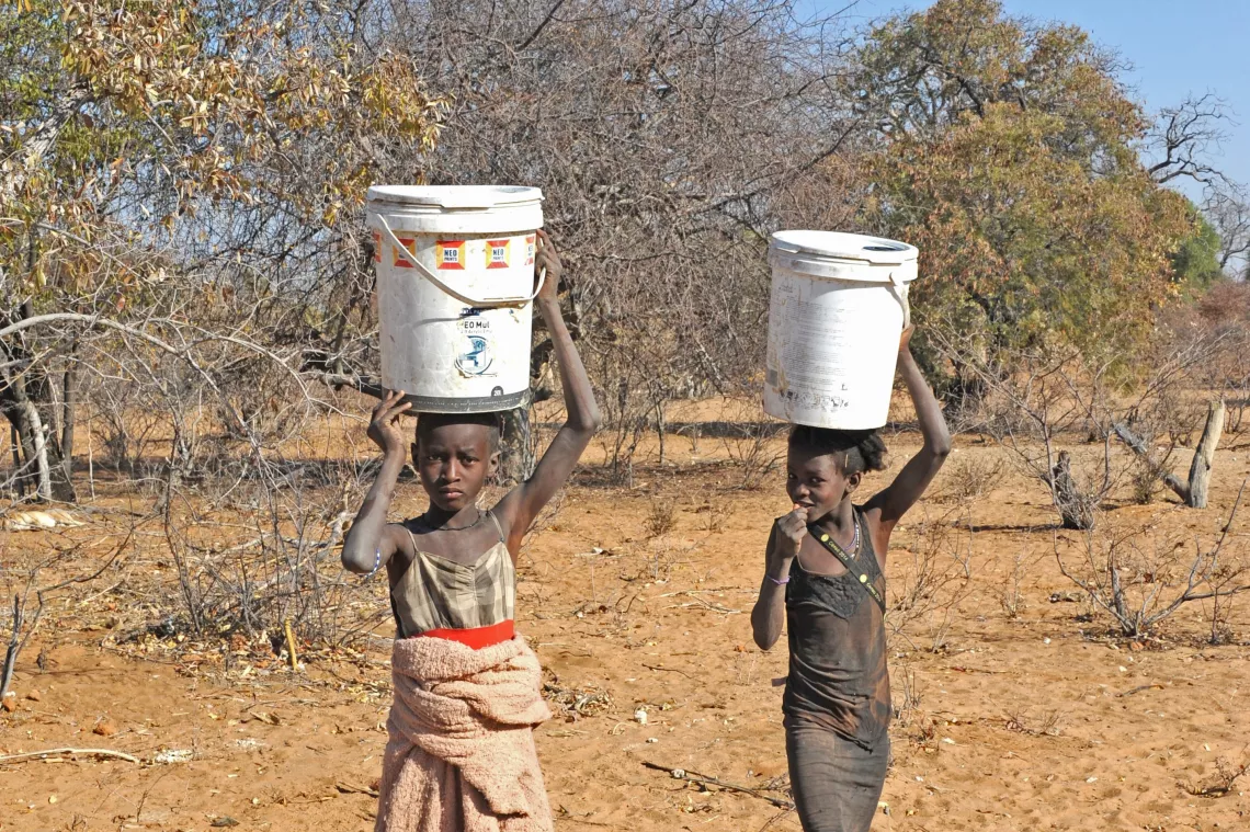 As meninas Onyevetu Laitia, 11 anos, e Marta Ndimaoshitya, 12, enfrentam mais de uma hora de caminhada para levar &aacute;gua para casa, na regi&atilde;o pr&oacute;xima &agrave; sede da comuna de Ombala-Yo-Mungo, munic&iacute;pio de Ombadja. A prov&iacute;ncia do Cunene e o Sul de Angola vivem uma seca extrema.