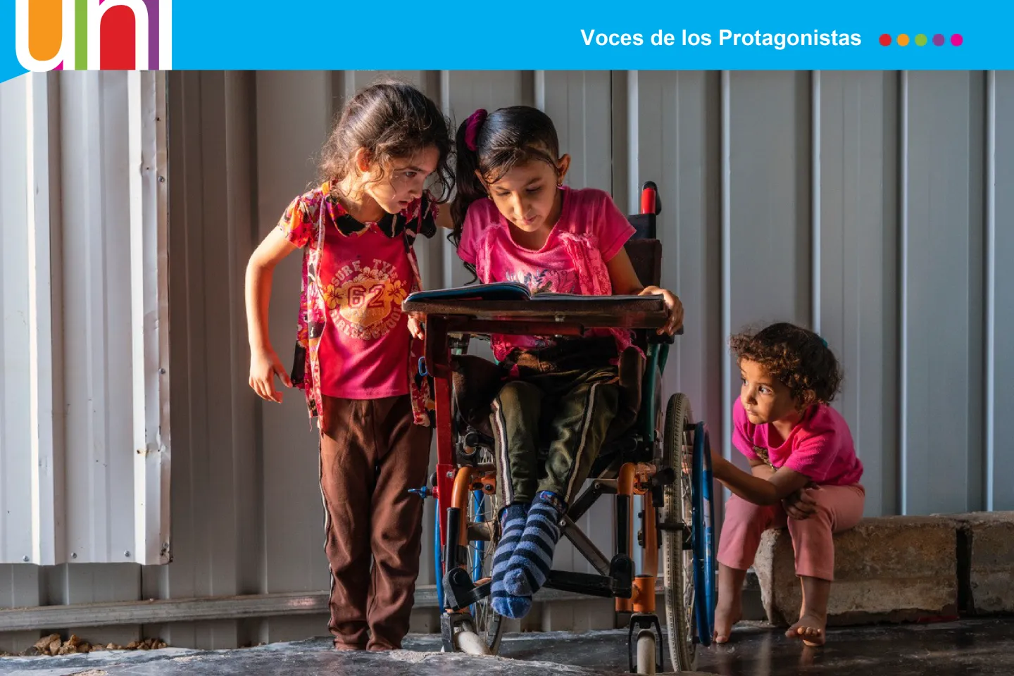 Tres ni&ntilde;as, una en silla de ruedas, leen un libro