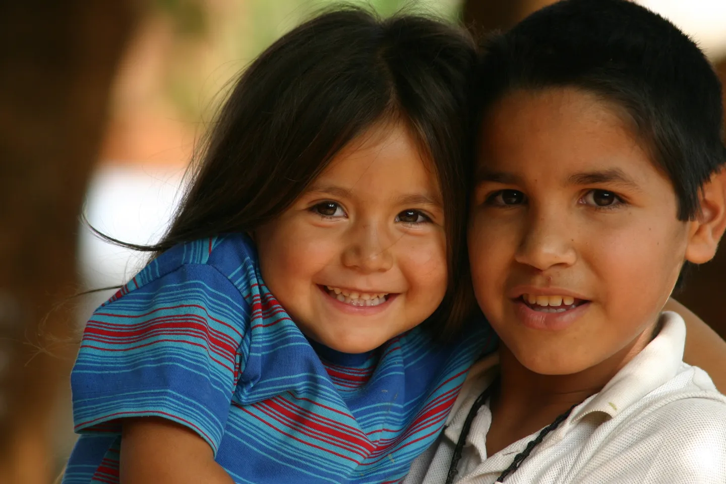 Un ni&ntilde;o y una ni&ntilde;a abrazados sonriendo a c&aacute;mara