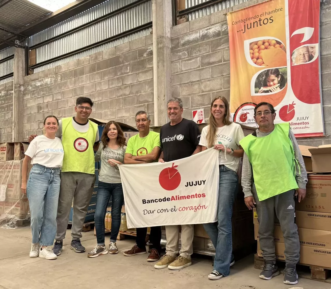 El equipo de UNICEF y de Banco de Alimentos sostienen una bandera de Bancos de alimentos Jujuy.
