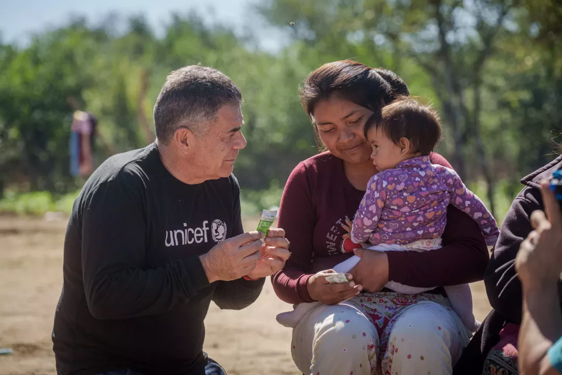 A la izquierda de la imagen, Juli&aacute;n Weich, hablando con una mam&aacute; y su beba a upa