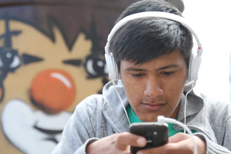 Adolescente con auriculares mirando el celular
