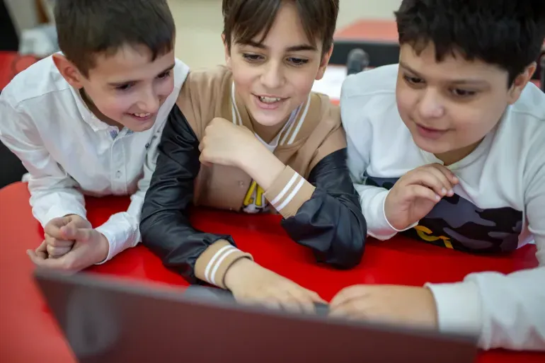 Tres ni&ntilde;os observan la pantalla de una computadora