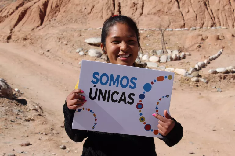 Una joven sosteniendo un cartel que dice ''Somos &uacute;nicas''