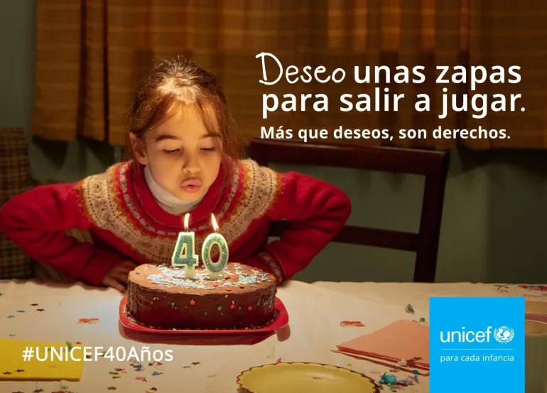 Una ni&ntilde;a soplando las velas con el n&uacute;mero 40 en una torta de chocolate