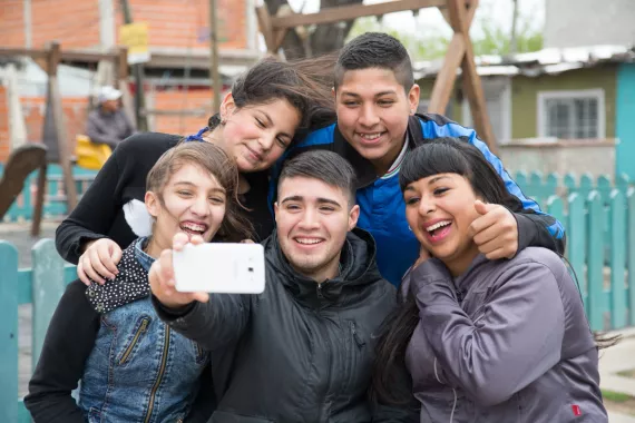 Un grupo de adolescentes sonríe mientras se sacan una selfie con un celular