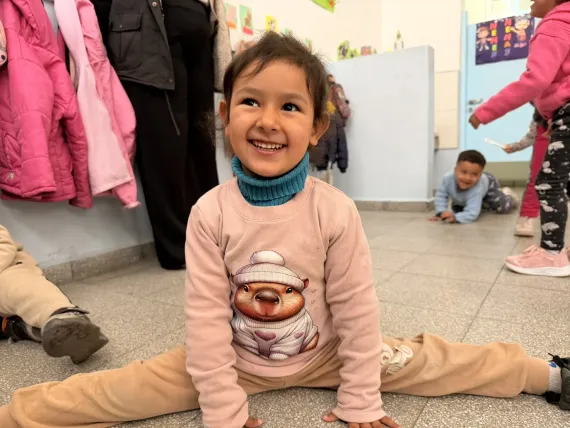 Ni&ntilde;a con ropa rosa est&aacute; sentada en el suelo sonriendo