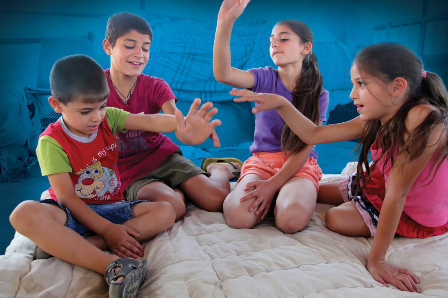  In a poor suburb lives this family with 11 children. Two boys and two girls playing a game sitting on the floor.