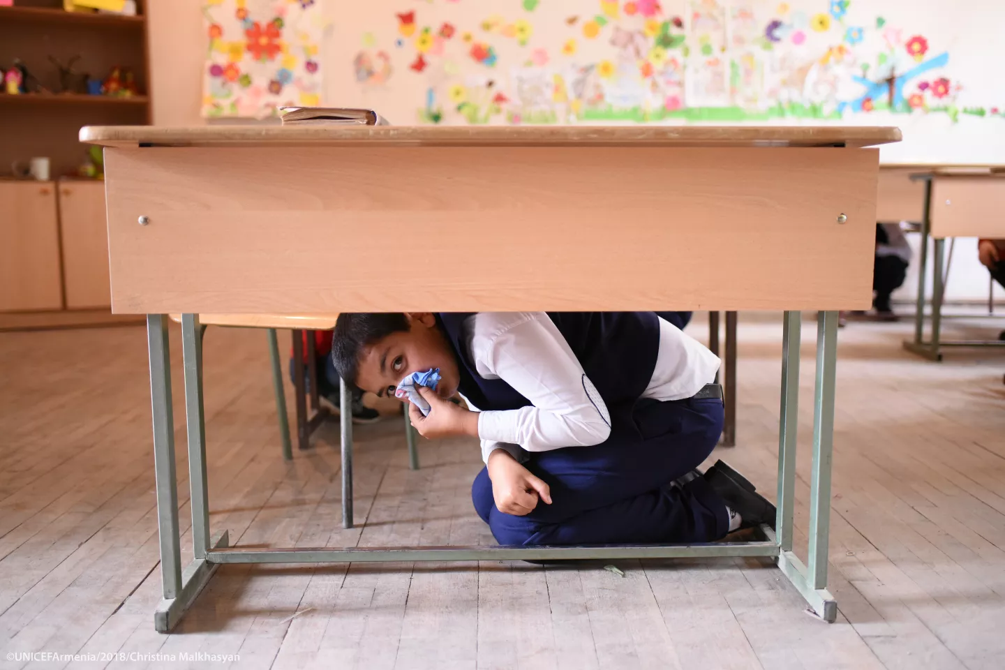 A school-aged boy hiding under the table during the DRR training organized by UNICEF Armenia and its partners in one of Ashtarak town schools.