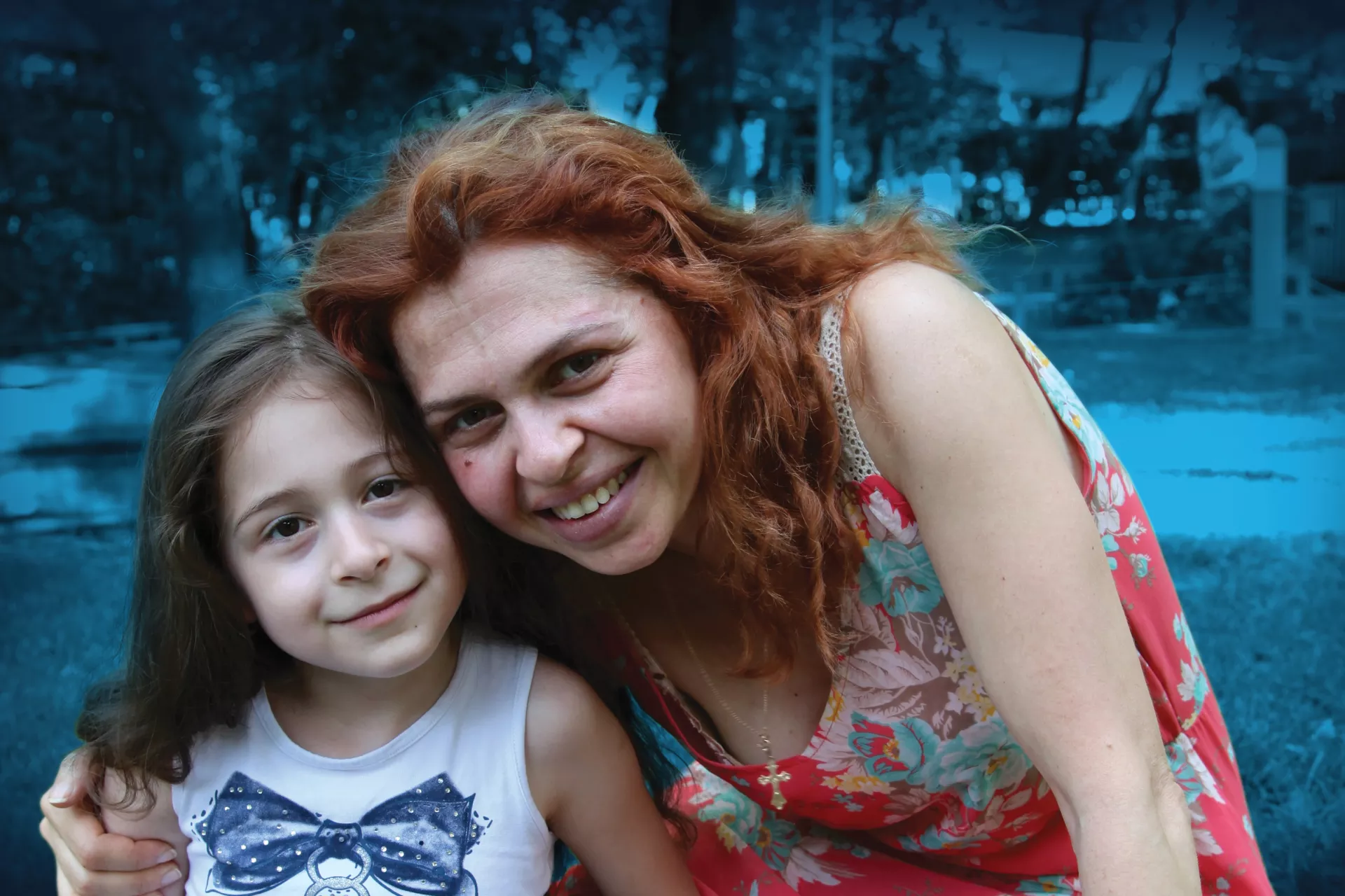 Mariam, 7, affected by cerebral palsy, sitting on the grass in the garden with her mother.