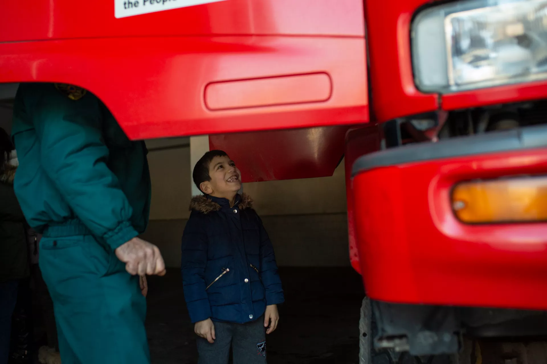 Boy is looking to the big red car with excitement. 