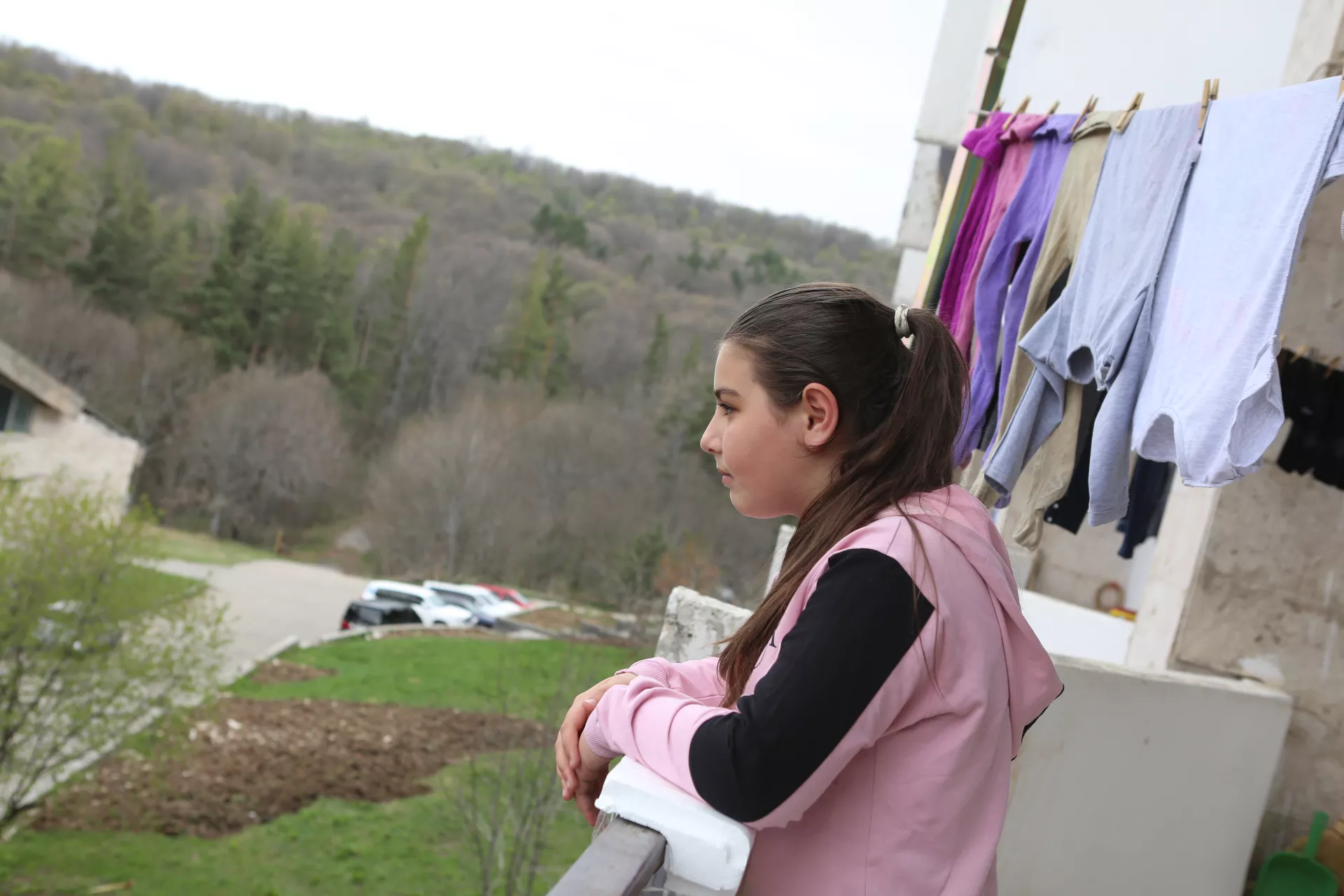 A young girl looking outside from the balcony