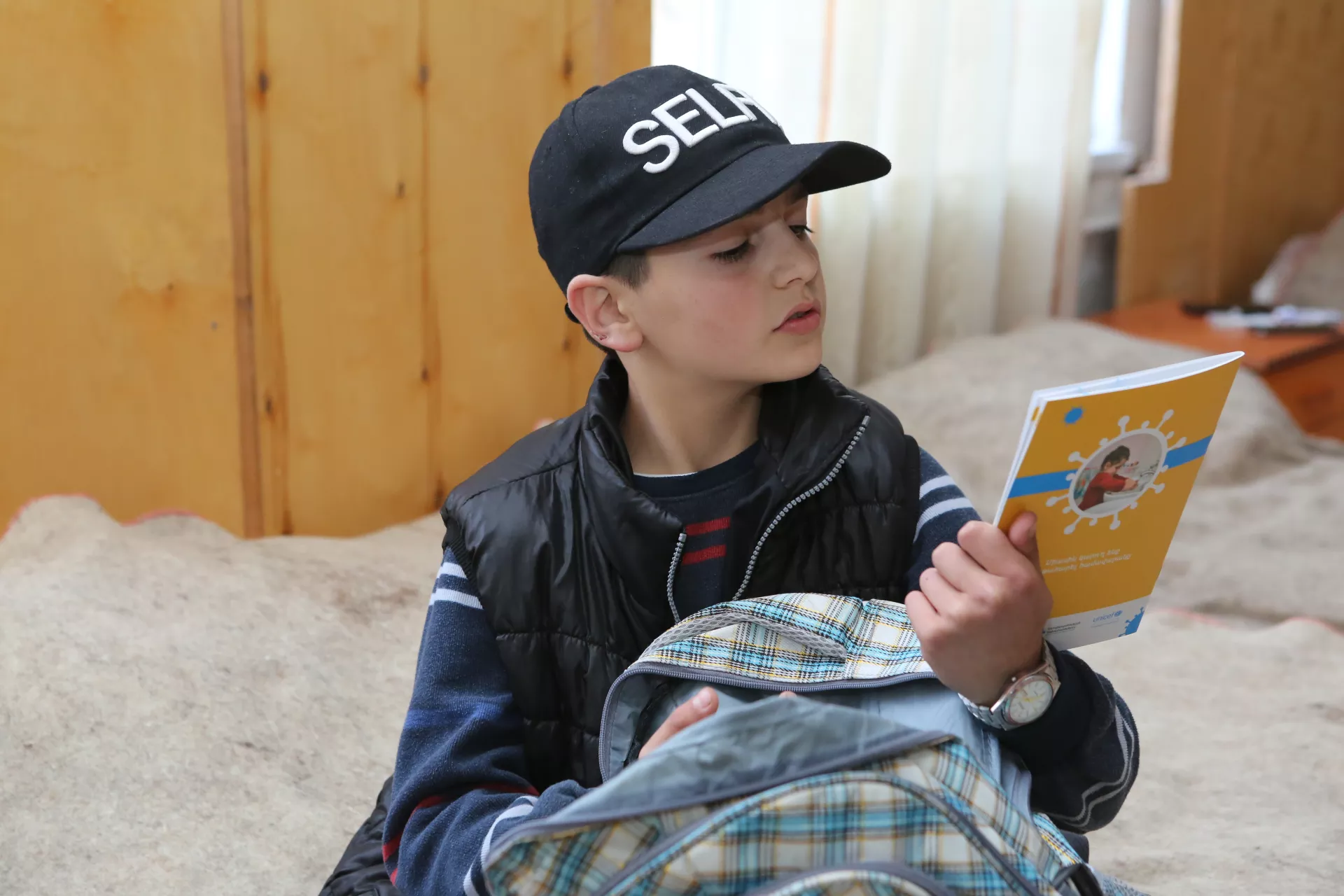 11-year old boy reading the cover of COVID-19 brochure