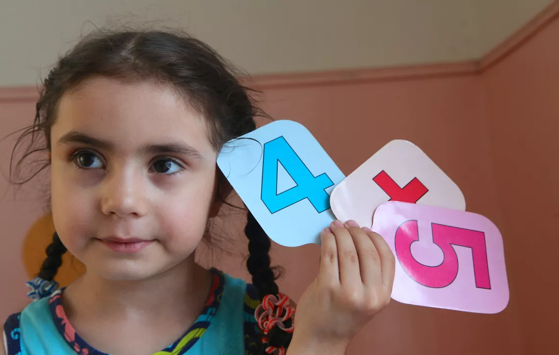 A girl holds numbers in class during a session. 