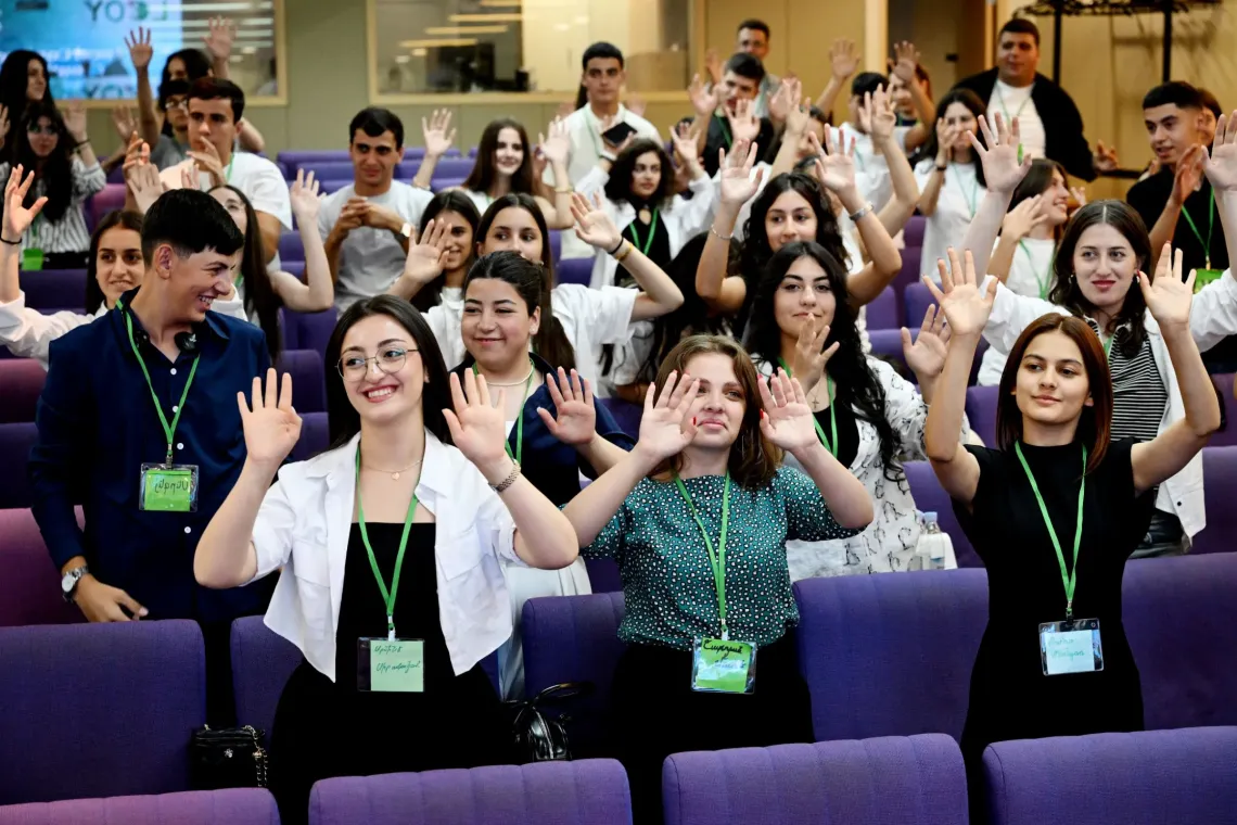 LCOY 2025 participants have raised their hands to applaud in sign language during a mini-session on sign language to welcome participants with disabilities.
