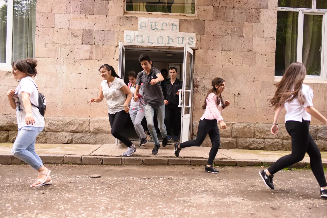 Children are running out from the school of Nerqin Tsakhkavan covering their heads with books during the evacuation drill.