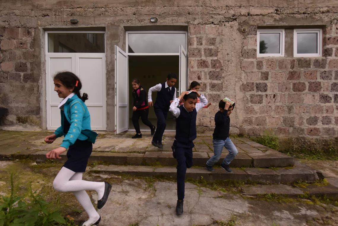 Children are running out from the school of Nerqin Tsakhkavan covering their heads with books during the evacuation drill.
