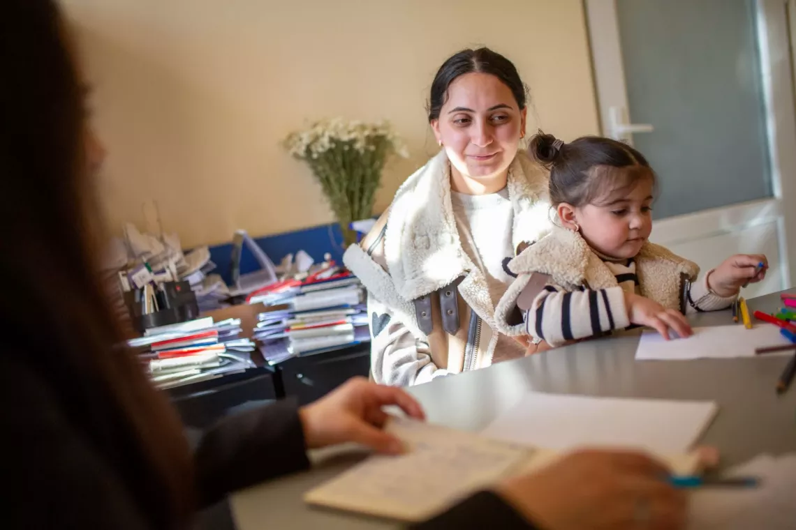 Mother and 3-4 y.o daughter at a session with psychologist. The child has colorful pencils in front of her