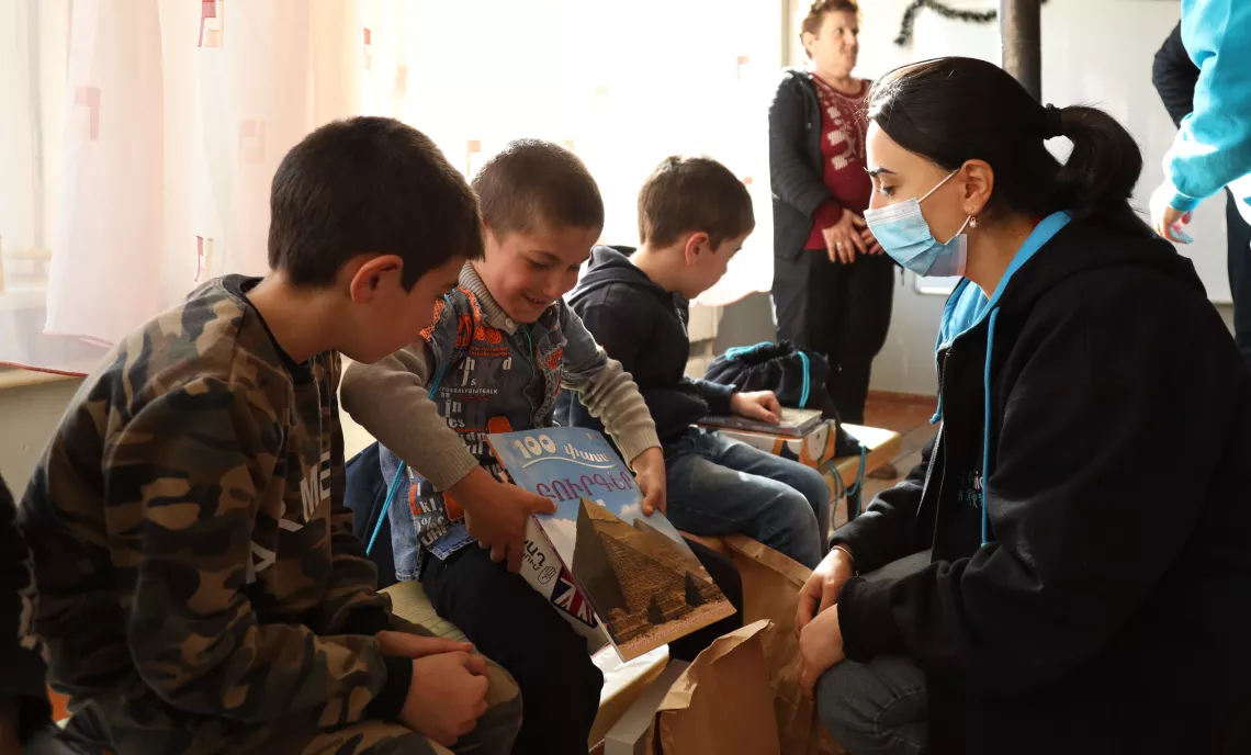 UNICEF employee talks to children who are opening presents. 
