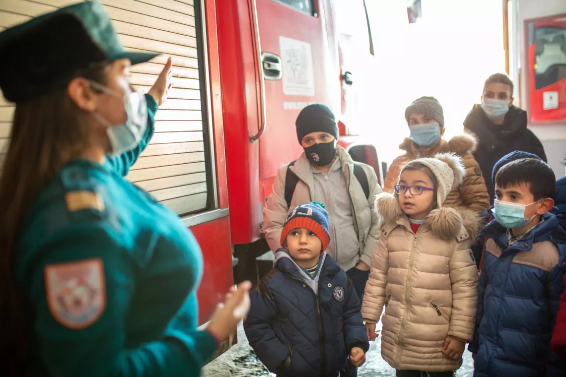 Children are attentively listening to Karine, a local firefighter.