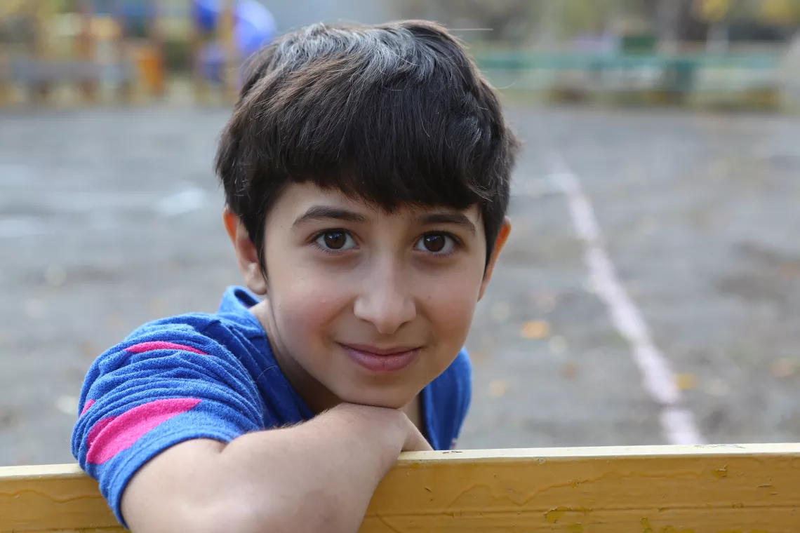 A 12-year old boy posing on a bench