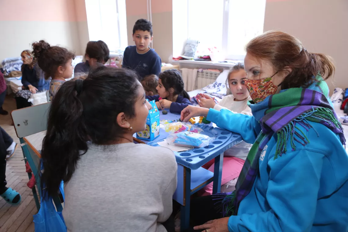UNICEF Representative talking and playing with children in a shelter