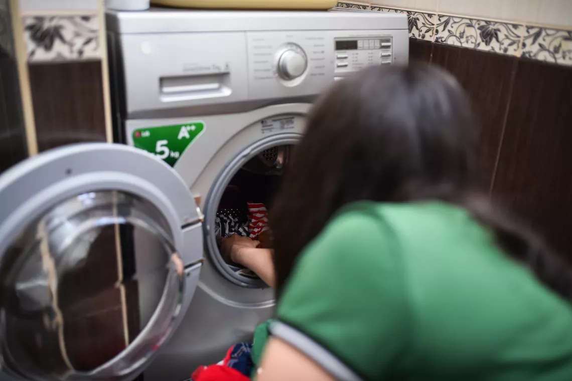 Կինը հագուստը լցնում է լվացքի մեքենայի մեջ։
