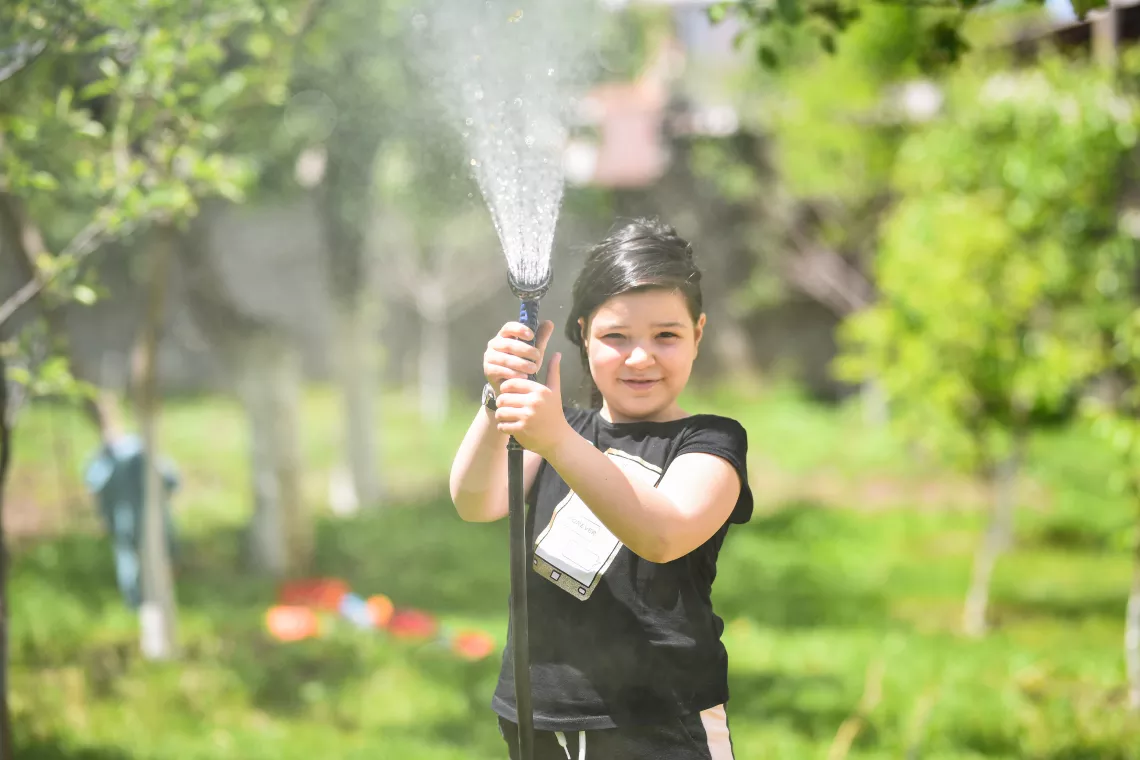 Girl is watering the trees.