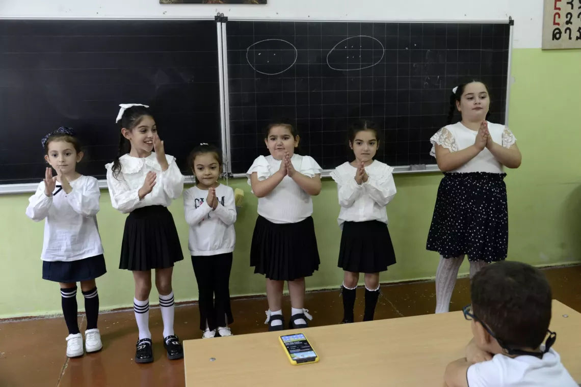 Arpi and her classmates in front of the black board in the classroom. 