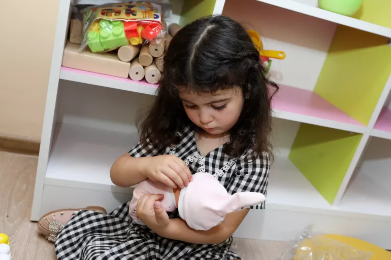 Փոքրիկ աղջնակը խաղում է տիկնիկով