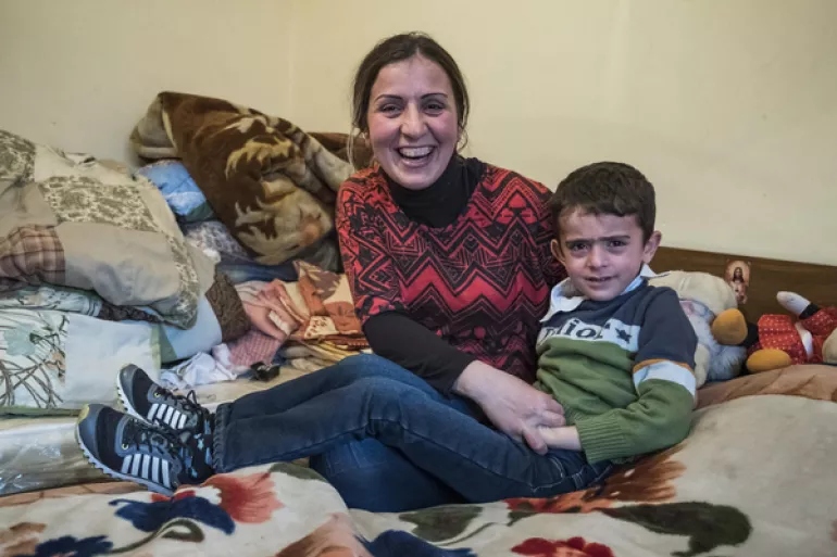Refugee mother with her son sitting on the bed in a temporary shelter