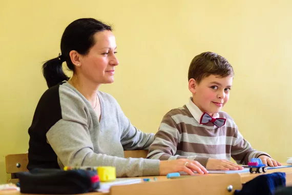 The mother helps her child with autism during the class in inclusive school in Yerevan.