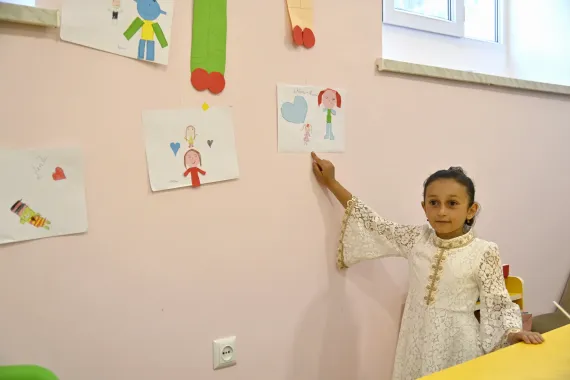 Viktoria, 7, proudly points to a colourful picture she made from pieces of paper hanging on the wall.