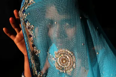 A teenage girl peers from behind a bridal veil