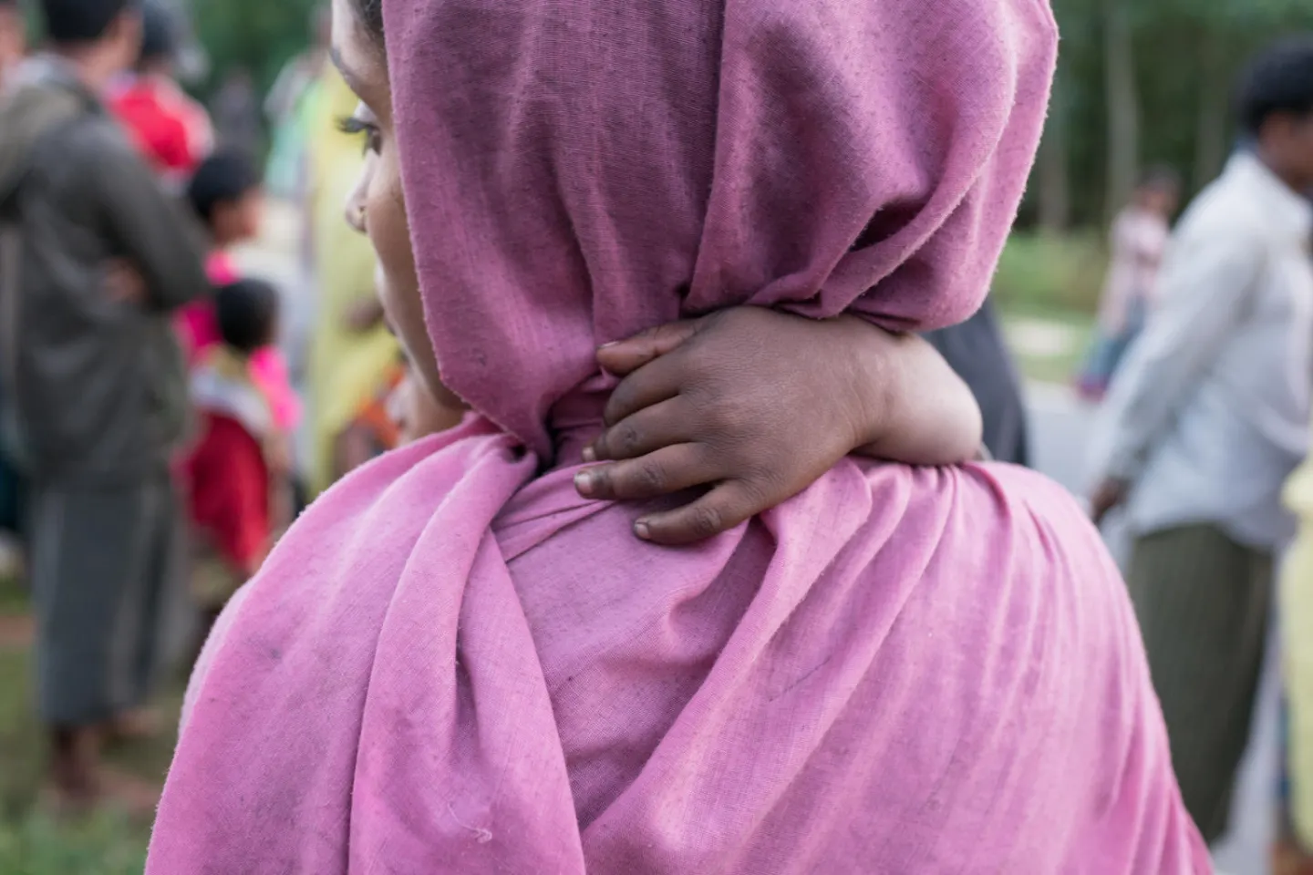 A Rohingya refugee baby holds on to its mother