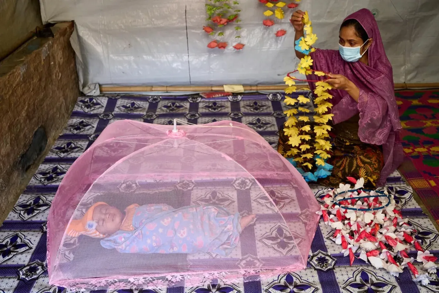 a baby is under a net tent with mom nearby