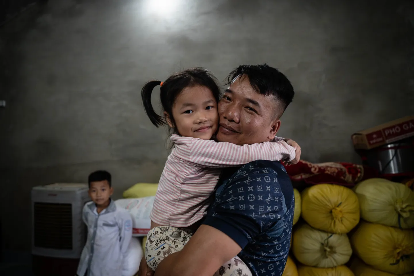 A father holding his daughter, both smiling at the camera