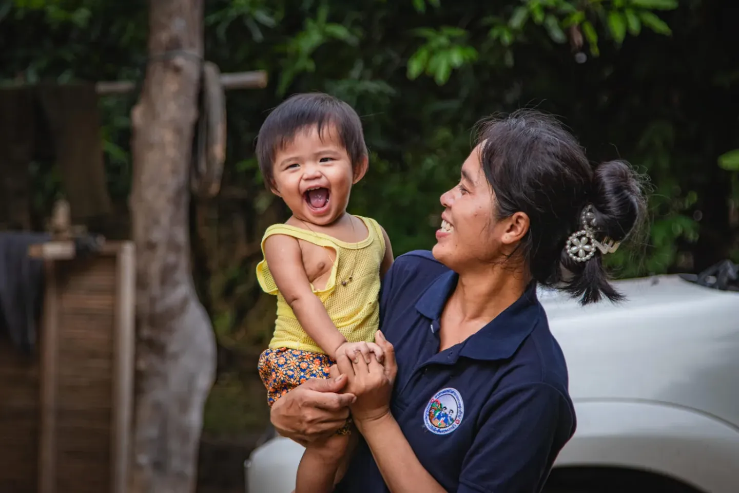 A smiling mother looking at the laughing toddler she is holding