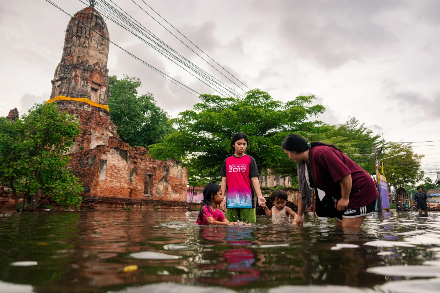 a woman stands in floodwaters with her children
